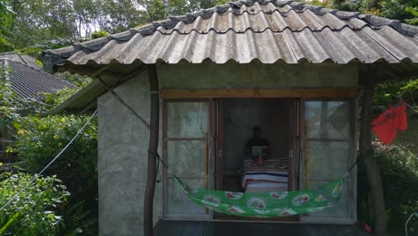 Man-sitting-with-laptop-on-bed-in-hut-homeoffice