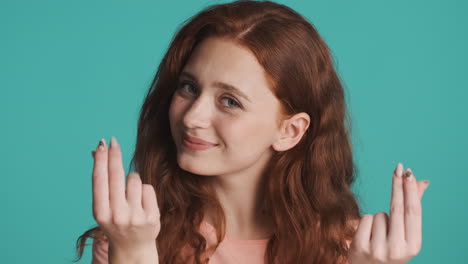 redheaded girl in front of camera on turquoise background.