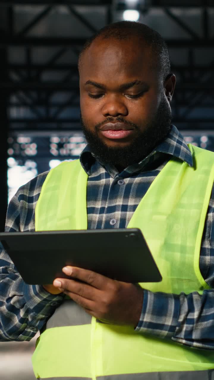 Vertical Video Factory supervisor checks assembly equipment on a tablet in manufacturing plant