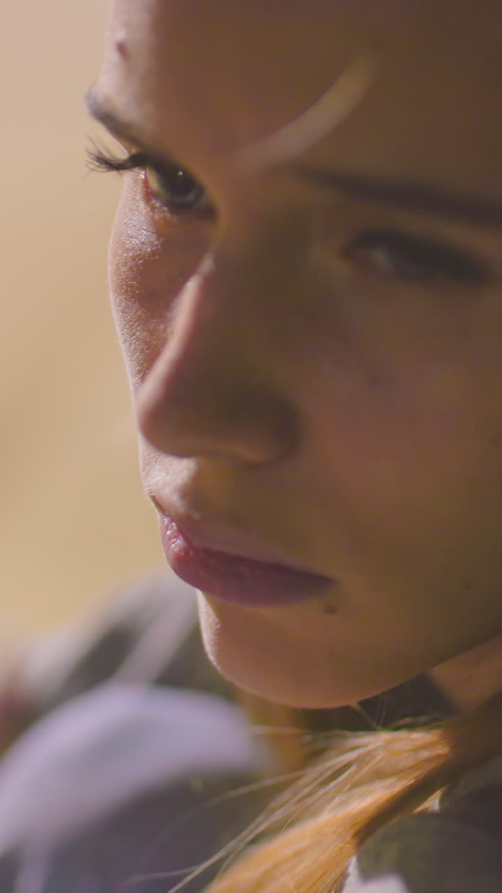 primer plano de una mujer al aire libre por la noche con una expresión cansada y somnolienta bajo una iluminación suave, el fondo sereno con vegetación borrosa y sombras sutiles se suma al estado de ánimo contemplativo