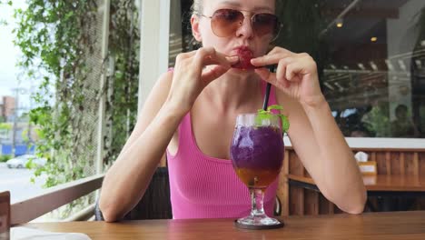 mujer disfrutando de un cóctel púrpura y fresa
