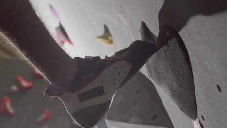 close up shot of an unrecognizable male sportsman climbing up bouldering wall indoors