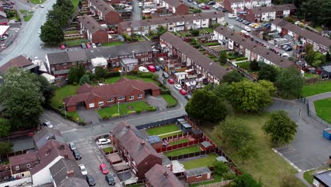 aerial view above british neighbourhood small town residential suburban property gardens and town streets slow tilt up