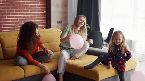 mother and her sister are playing with balloons with blondy small girl