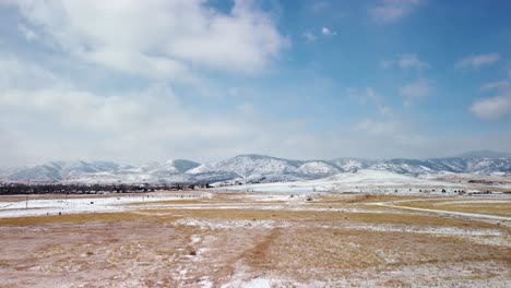 flying over snowy fields towards the foothills of the colorado rockies during the day, aerial