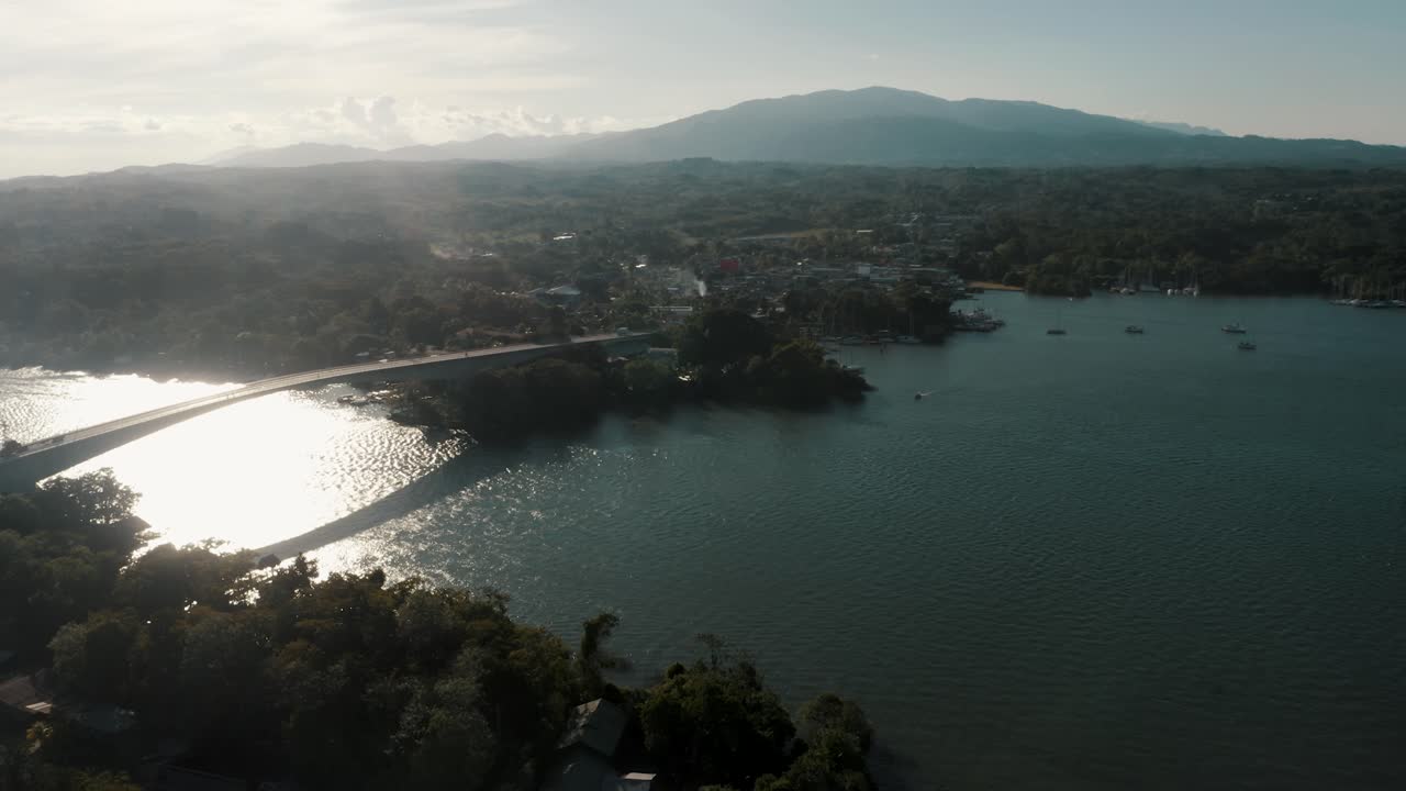 Vista aérea do Lago Izabal numa manhã ensolarada com a Puente de Rio Dulce revelada.