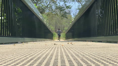 Hombre-Corriendo-En-Un-Puente-Hacia-La-Cámara-En-ángulo-Bajo