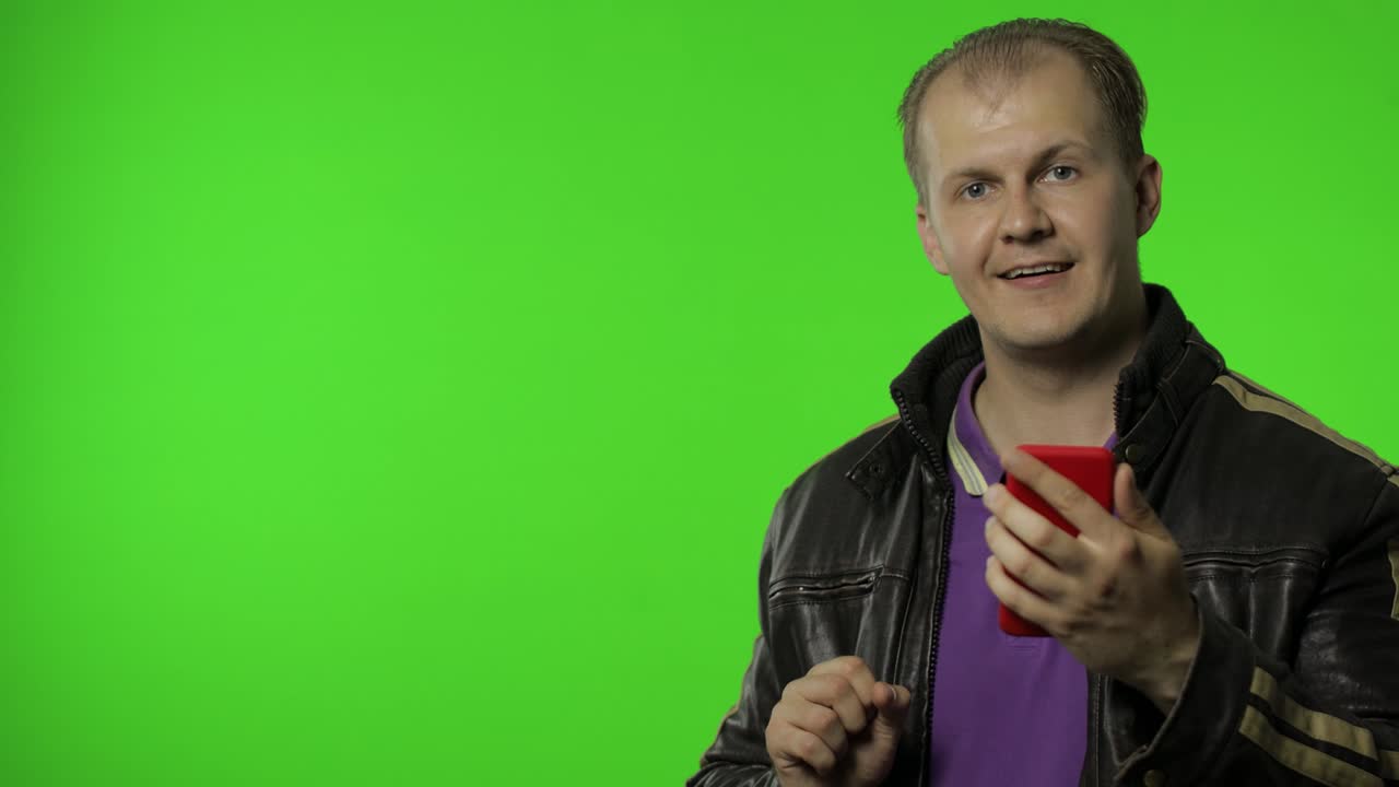 hombre rocker mostrando área de publicidad lateral. usando teléfono inteligente, apuntando a la pared para su texto, logotipo