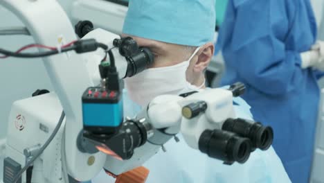 surgeon looking into the microscope at the eye of female patient at the operating room. doctor using microscope during eye surgery process, treatment of cataract and diopter correction.