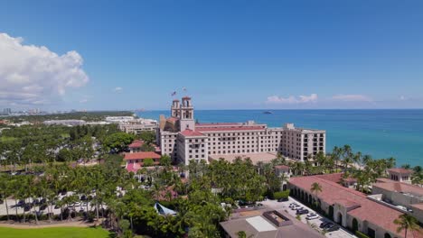 Kreisende-Aufnahme-Eines-Gebäudes-Aus-Der-Luft-Mit-Drohnenansicht-Der-Innenstadt-Von-West-Palm-Beach-Und-Wunderschönem-Strandsand-Und-Booten-Im-Wasser