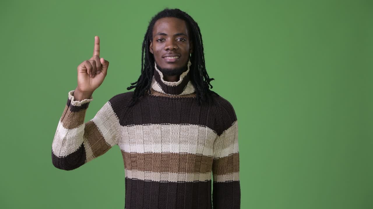 Young handsome African man with dreadlocks against green background