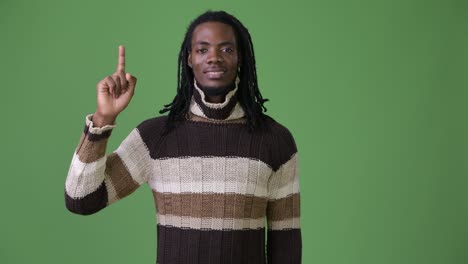 young handsome african man with dreadlocks against green background