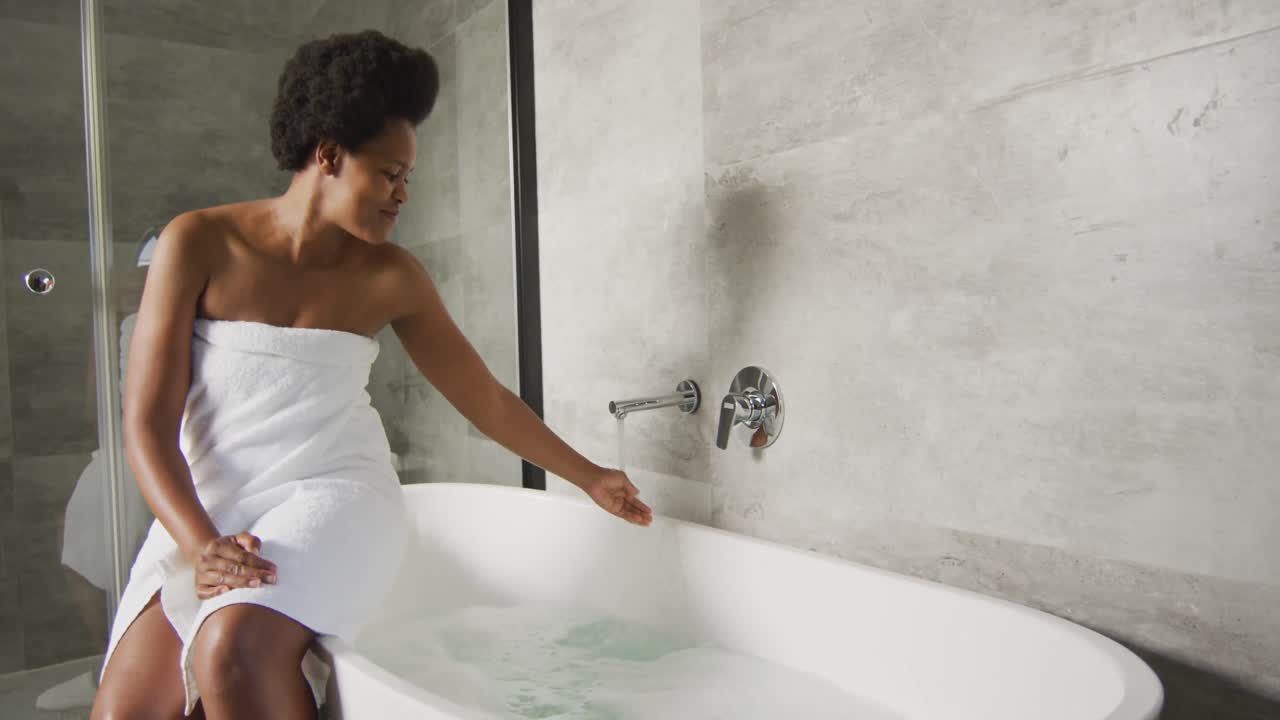 Happy african american woman preparing bath in bathroom