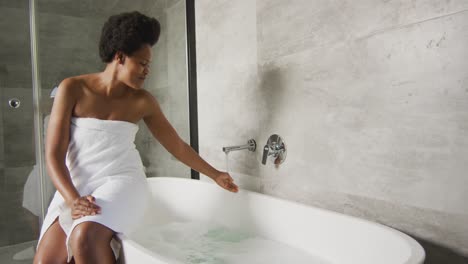 feliz mujer afroamericana preparando el baño en el baño