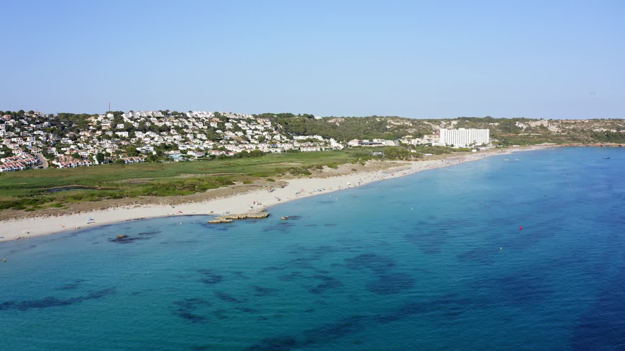 스페인 메노르카의  ⁇  부 해변에서 휴식을 취하고 있는 사람들. 크리스탈처럼  ⁇ 은 파란 물과 럭셔리 부동산이 배경입니다.
