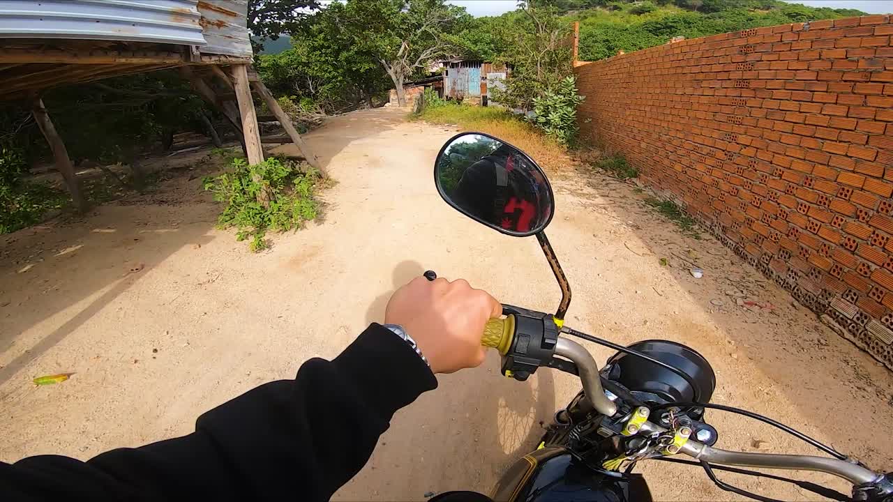 Man driving motorcycle on road amid orchard in Vinh Hy, Vietnam, POV