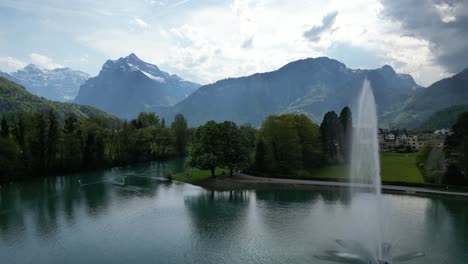 Cuenca-De-Agua-Del-Lago-Frente-A-Un-Pequeño-Pueblo-En-Gäsi-Betlis,-Walensee-Glarus,-Weesen-Walenstadt,-Suiza--Vista-De-Drones