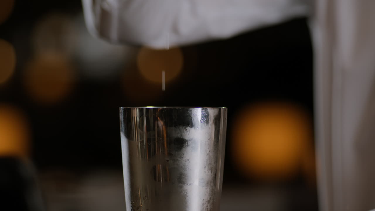 Primo piano di un barista che apre uno shaker per cocktail dopo averlo miscelato