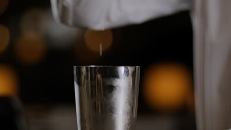 closeup shot of a bartender opening up a cocktail shaker after mixing it