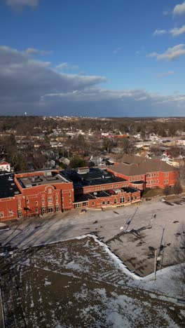 aerial vertical establishing of suburban school surrounded by houses with cityscape in the distant background