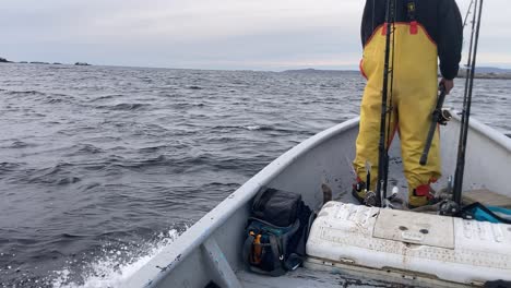 fisherman stands at bow of boat on gloomy day