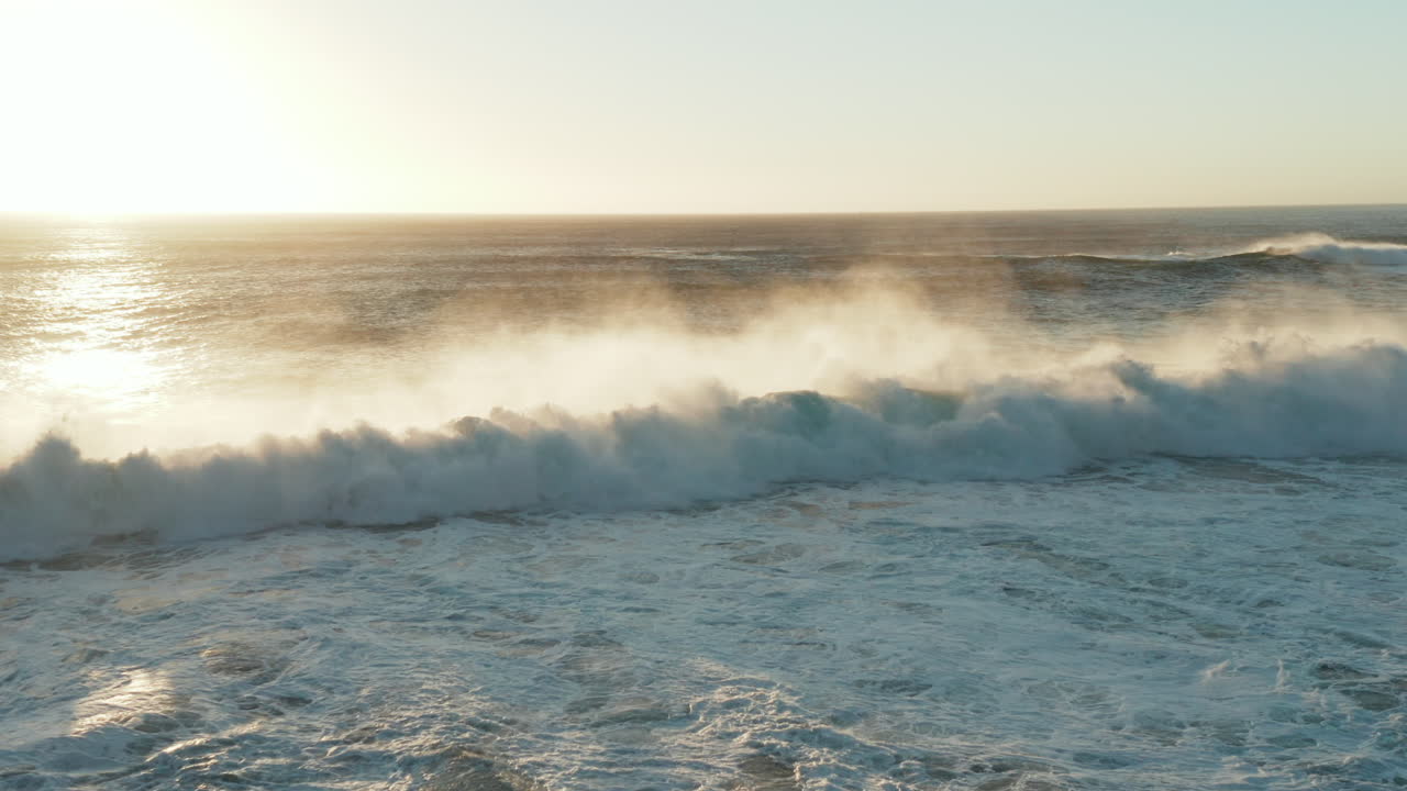 Aerial of big waves breaking on the shore of Llandudno beach with sunset in Cape Town, South Africa