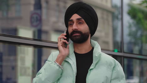 hombre indio hablando por teléfono mientras camina por la ciudad