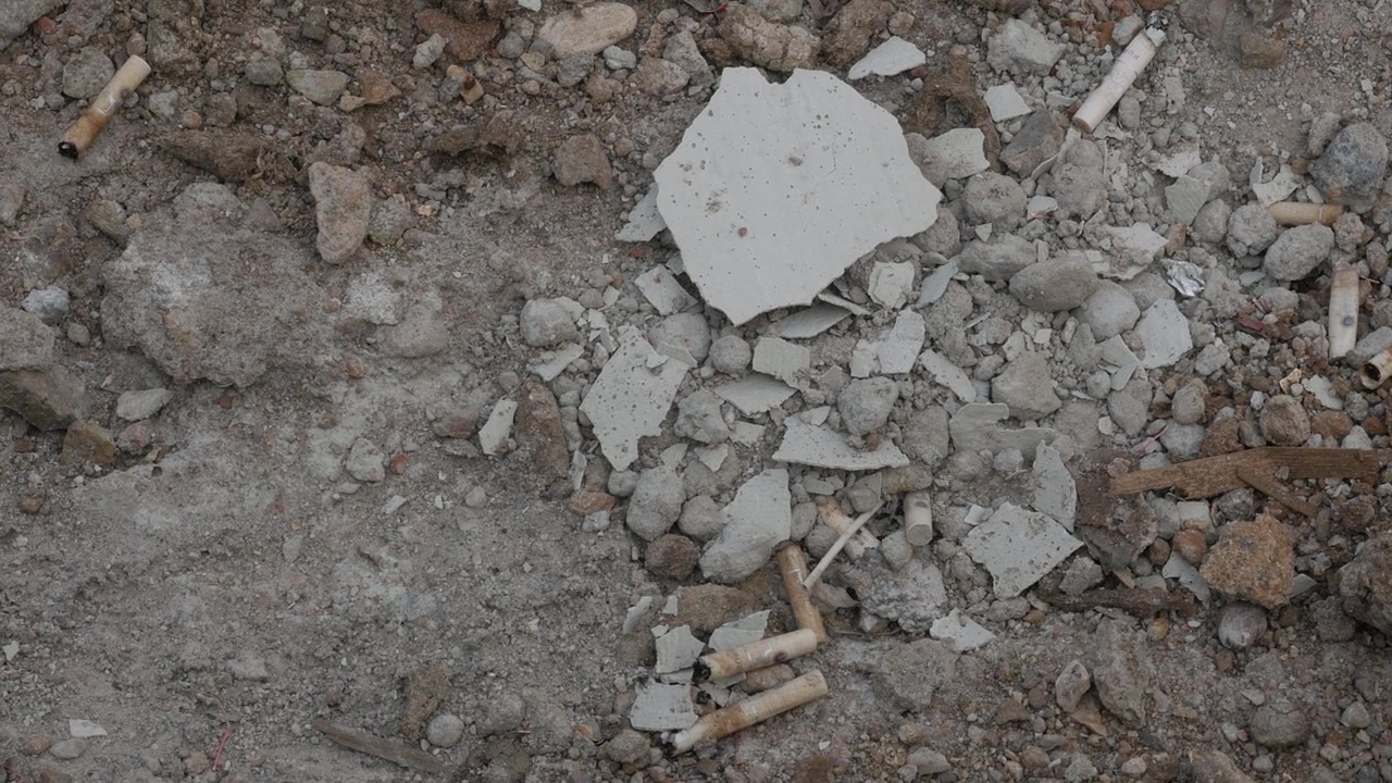 Cigarette Butts and Construction Debris on Gravel Ground