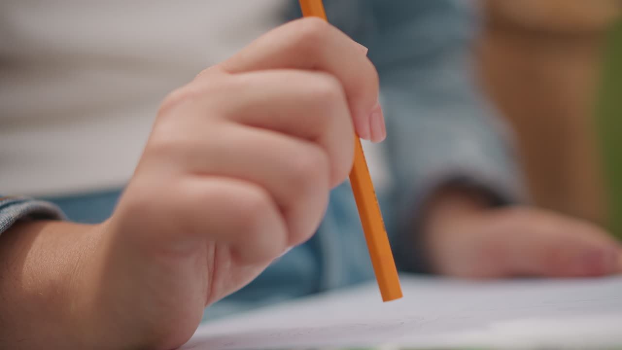 Esboçando com lápis. Close-up de mão esboçando. Imagem focada capturando mão e lápis em detalhe. Tomada precisa enfatizando a mão segurando o lápis entre cadernos e elementos de fundo
