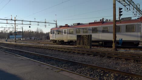 un tren eléctrico de pasajeros que sale de la estación de tren en una pequeña ciudad sueca