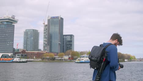 portrait of an analog film photographer on ij riverbank in the city of amsterdam, the netherlands