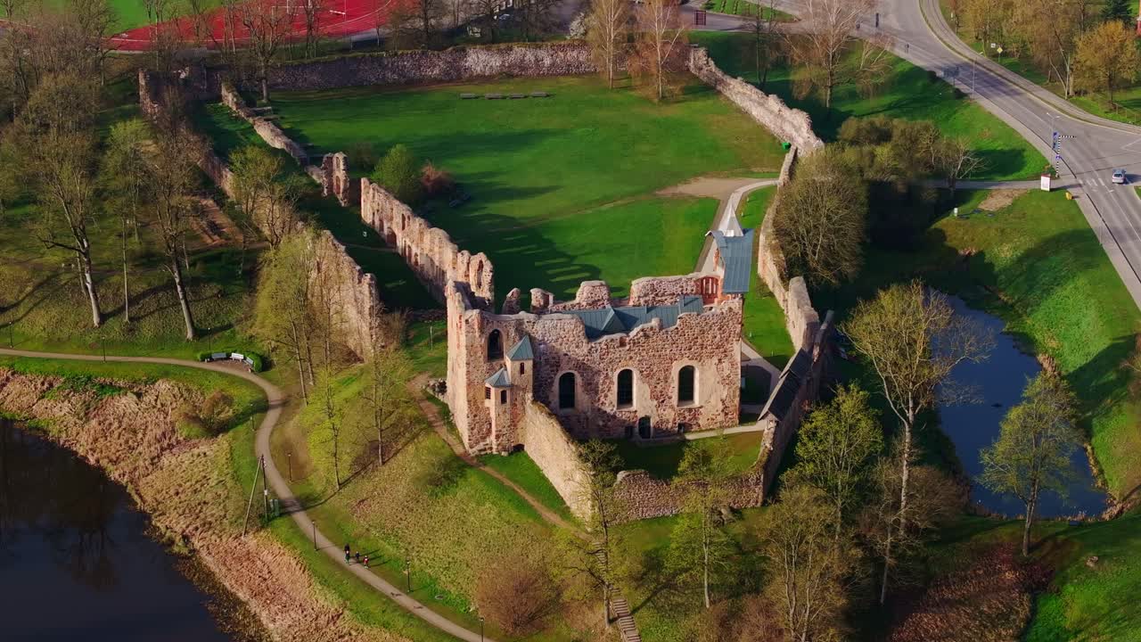 Dynamic aerial of historic stone medieval Dobele Castle, fresh green grass
