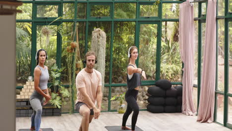 practicing yoga, group performing poses on mats in glass house studio
