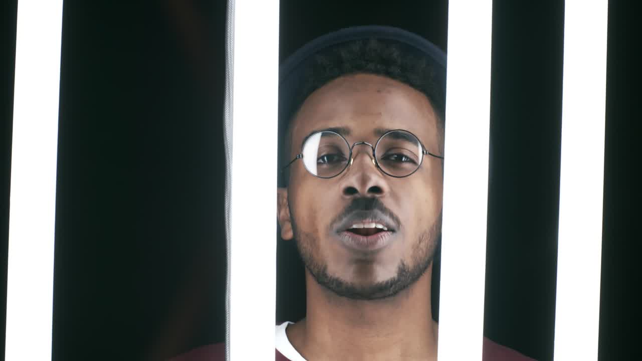 Stylish Musician Singing behind Fluorescent Tubes