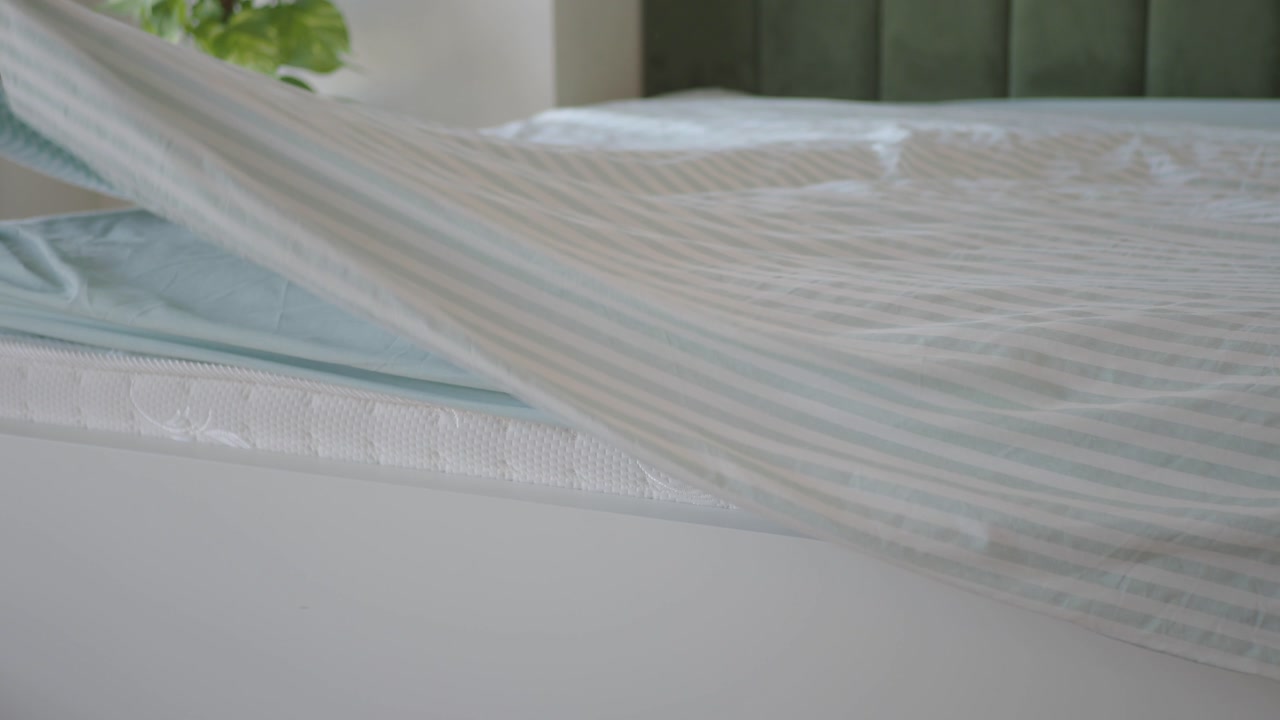 Person Making Bed with Striped Duvet Cover