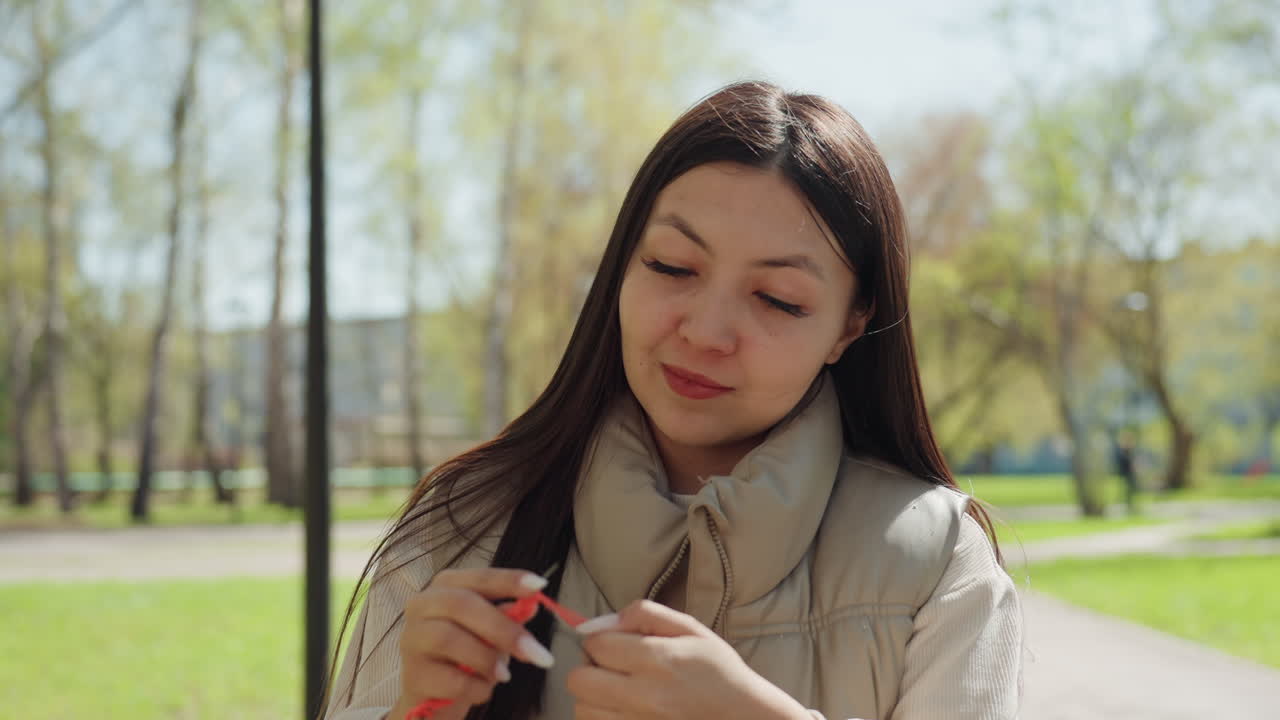 따뜻한 봄날 오후, 공원에서 편안하게 뜨개질하기. 꽃이 만발한 나무들 사이에서 열정적으로 뜨개질하는 사람. 봄에 공원을 배경으로 질감 있는 털실로 무언가를 열심히 만드는 사람