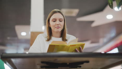 el novelista que lee el libro amarillo en un restaurante moderno pasa a la siguiente página con una sonrisa sutil, reflejando la relajación y el compromiso intelectual.