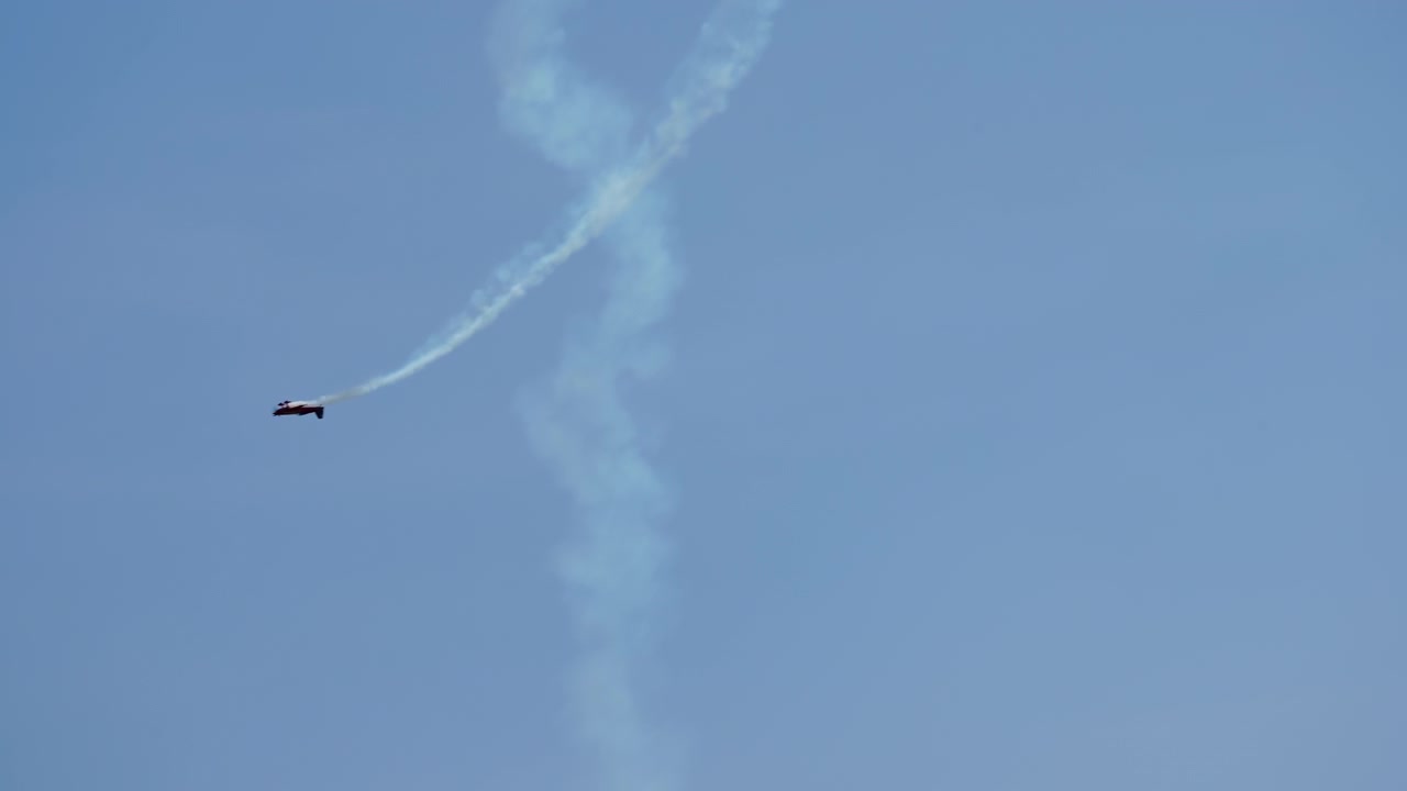 Aerobatic aircraft climbing vertically with long smoke trail in sky