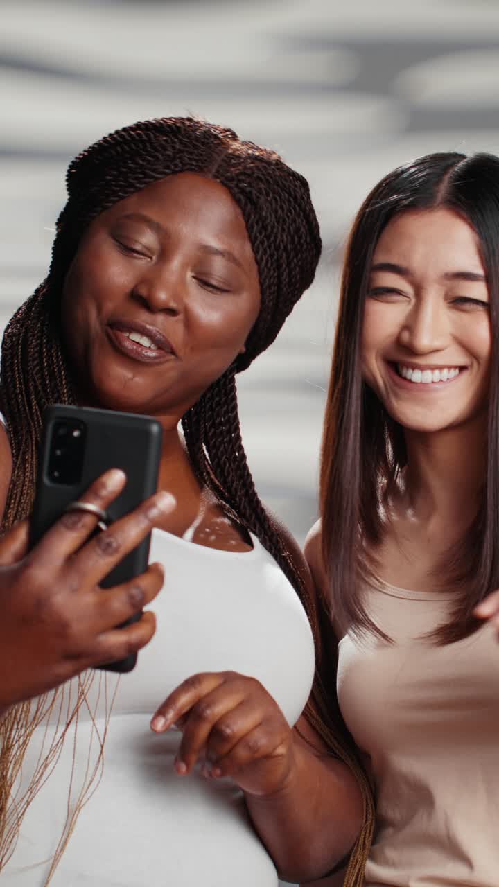 Vertical video: Interracial cheerful ladies taking photos with phone