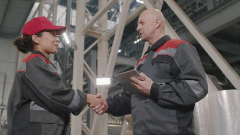 foreman shaking hand to factory worker