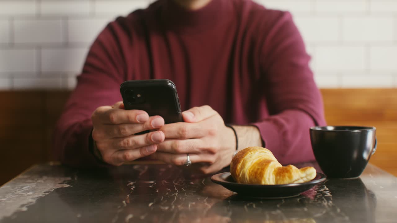 hombre usando el teléfono y disfrutando del desayuno en un café