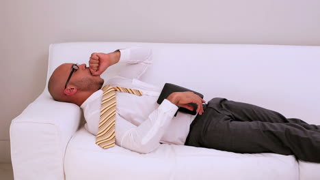 Tired businessman falling asleep on couch