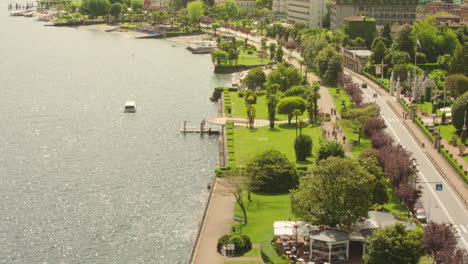 toma aérea del bulevar stresa con jardines verdes que se encuentran con el lago maggiore