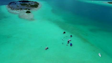 drone aerial landscape of people swimming with tour boats docked on sandbar lagoon lake inlet island snorkelling spot bacalar town village mexico travel holidays tourism