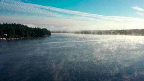 lake fog rises mystically across crystal blue water on magical morning by washington forest