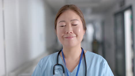 young asian nurse stands confidently in a hospital corridor