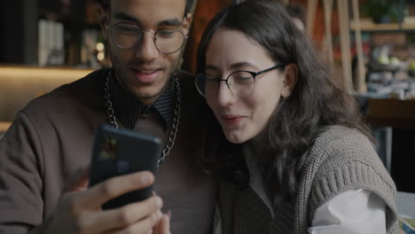 young couple looking at smartphone in a cafe