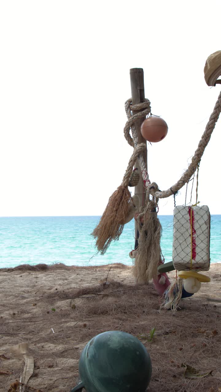 Inquadratura media statica di galleggianti da pesca e corde appesi su una spiaggia tropicale soleggiata
