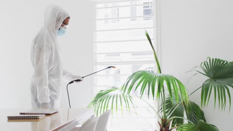 health worker wearing protective clothes cleaning the office using disinfectant