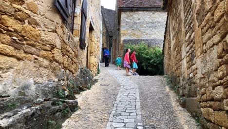 family walking through the pretty medieval cobbled streets of beynac, france